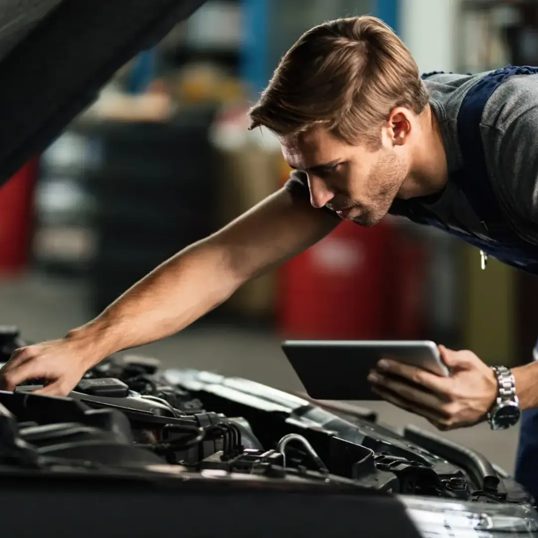 Car mechanic examining engine malfunction while using touchpad in auto repair shop